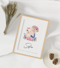 Exemplo de quadro personalizado "Menina" com ilustração de bebé a dormir num baloiço, fundo rosa suave. Ideal para decoração de quarto infantil.