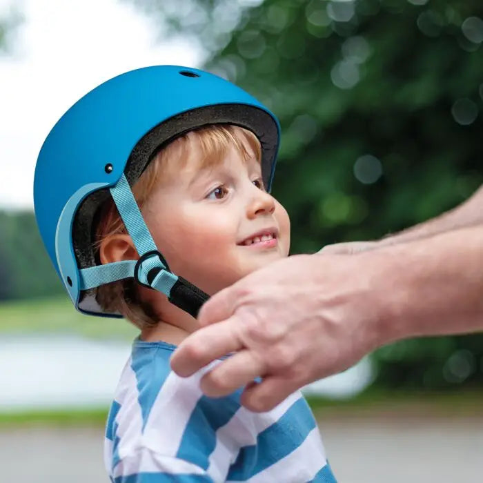Criança a usar capacete Shoko azul, adulto ajusta correia. Proteção infantil 3-7 anos, 50-55cm.