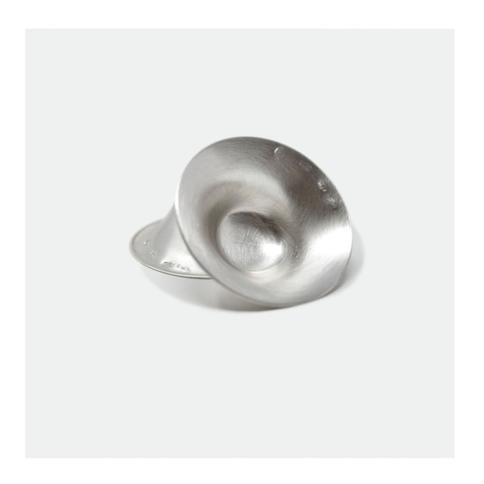 Ilustração mostrando a aplicação do mamilo de prata no peito, com uma gota de leite visível, conforme o método de uso recomendado.