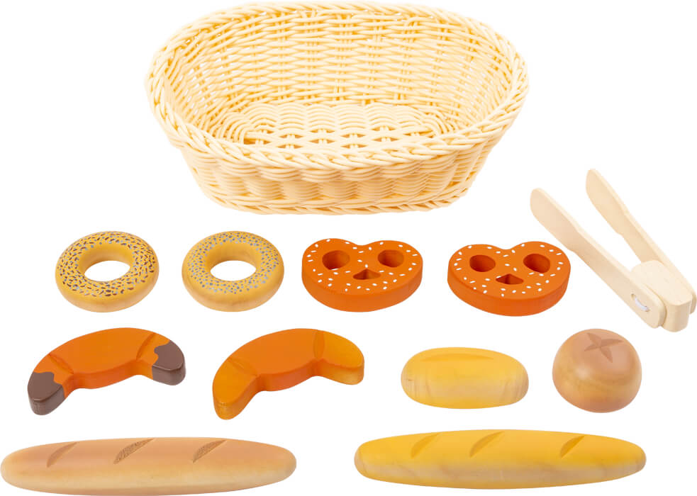 Detalhe da cesta de tecido com diversos pães de brincar em madeira, incluindo um pão de trigo e um pão de centeio.
