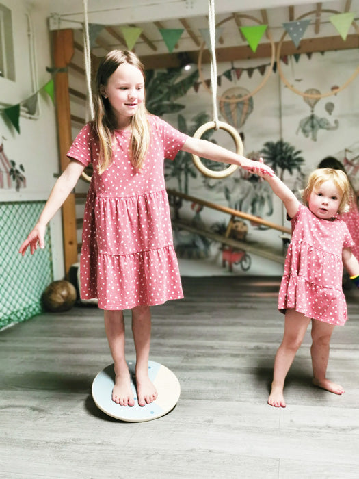 Tábua de equilíbrio redonda em madeira natural, vista superior, com duas bolas de madeira aparafusadas na parte inferior para treino de equilíbrio.