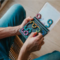 Mãos a jogar o SmartGames IQ Digits, mostrando o mecanismo de encaixe das peças magnéticas no tabuleiro.