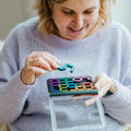 Mulher a jogar o SmartGames IQ Digits, mostrando a concentração e a diversão do jogo.