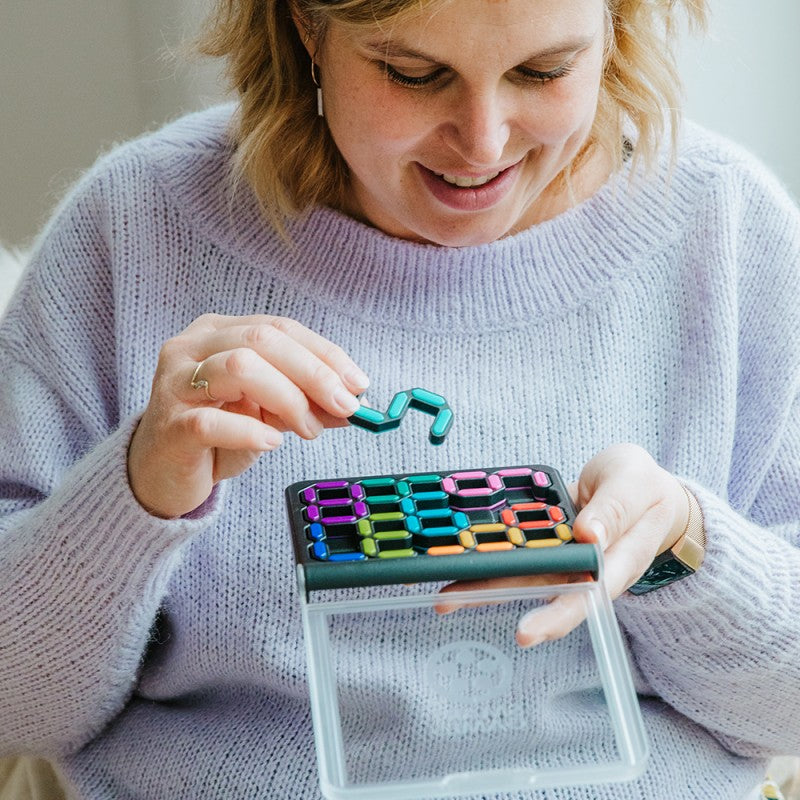 Mulher a jogar o SmartGames IQ Digits, mostrando a concentração e a diversão do jogo.