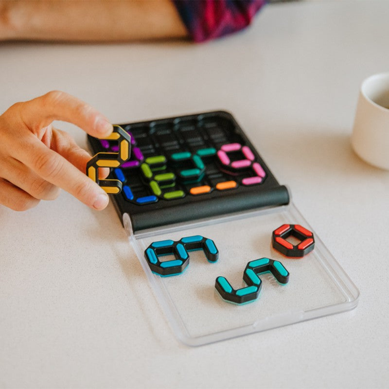 Mãos a colocar uma peça no SmartGames IQ Digits, mostrando a interação com as peças magnéticas.