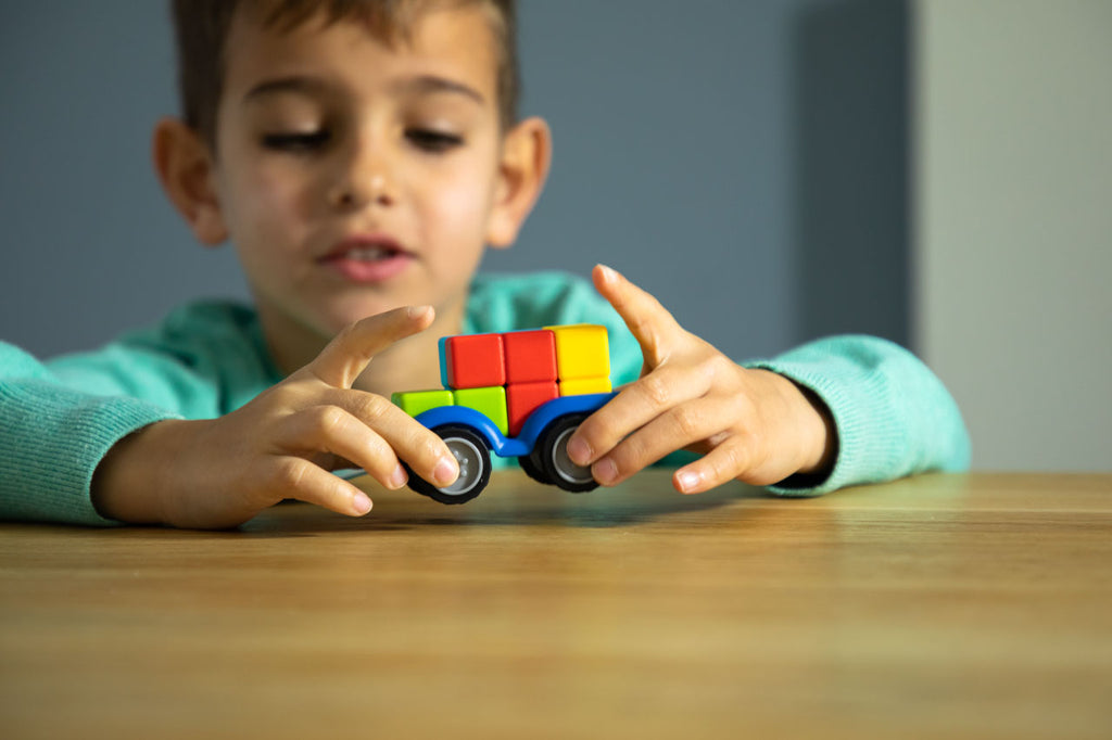 Criança a brincar com o SmartGames SmartCar Mini, focando na interação e diversão do jogo.