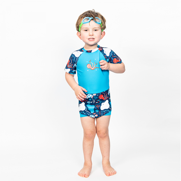 Fato de banho UV Splash About Happy Nappy Sunsuit "Under The Sea" em criança, mostrando o design completo com mangas 3/4 e padrão marinho.
