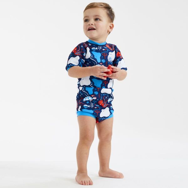 Criança a usar o fato de banho térmico Splash About Happy Nappy Wetsuit na piscina, exibindo o ajuste seguro e as mangas compridas.