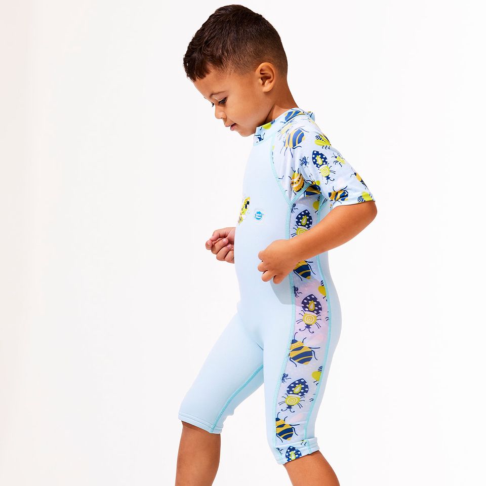 Criança de perfil a ajustar o fato de banho térmico Splash About Bugs Life, destacando o design justo e os painéis laterais estampados.