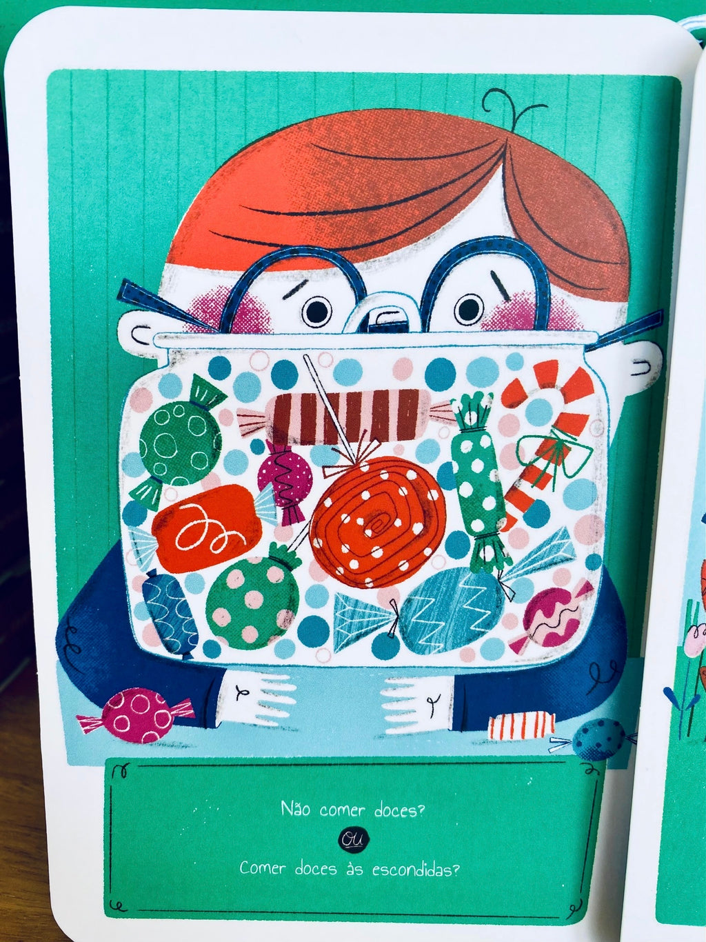 Criança (ou mãos de criança) a interagir com as cartas e o livro, ilustrando o uso prático do jogo para desenvolver a capacidade de escolha e reflexão.