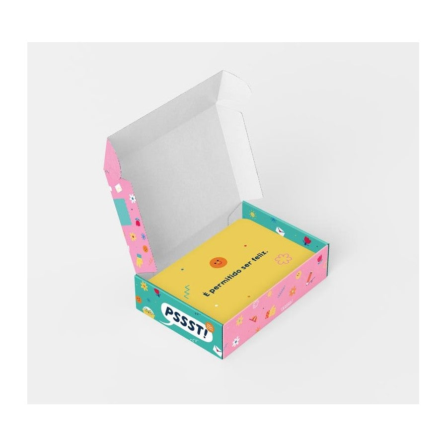 Vista aérea (flat lay) de vários cartões coloridos "Pssst" do produto, exibindo mensagens curtas de afeto e positividade.