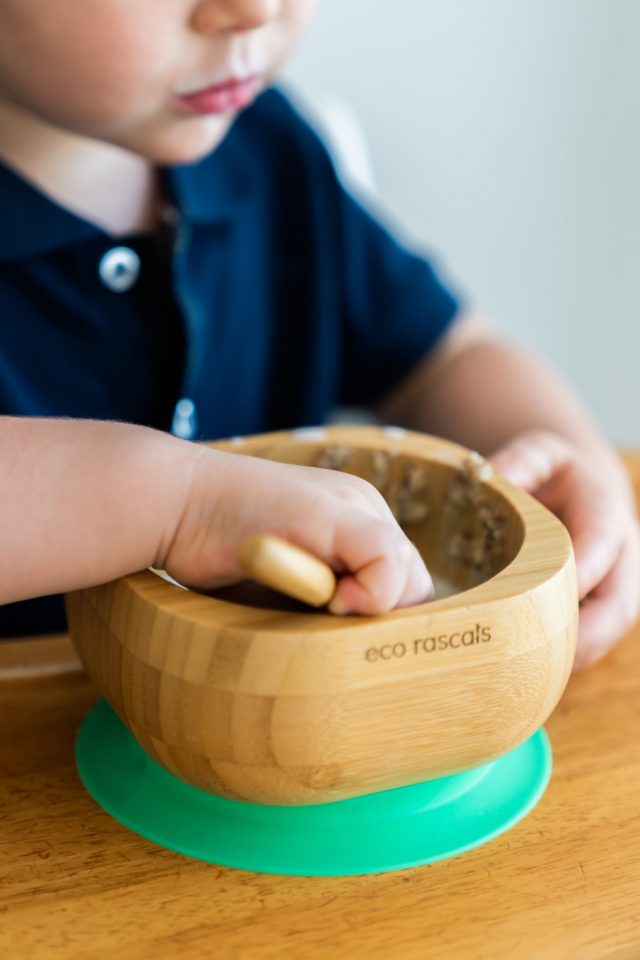Bebé a comer autonomamente com a colher na tigela de bambu eco rascals com ventosa verde