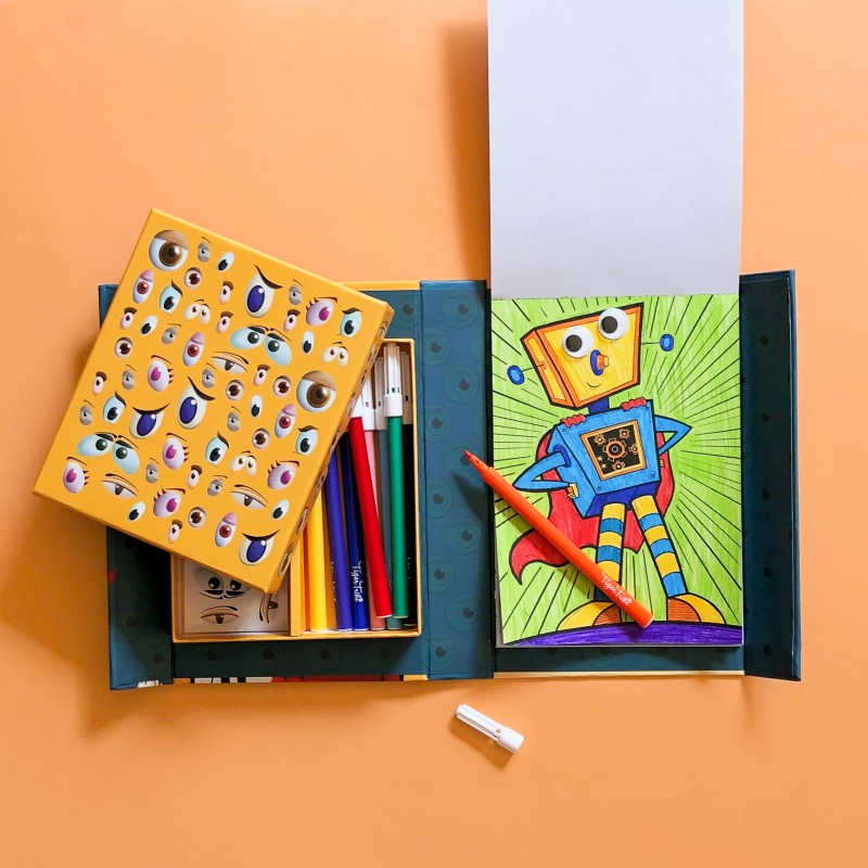 Demonstração de uso do kit Tiger Tribe com um desenho de um robô super-herói colorido, com olhos autocolantes e um marcador laranja.