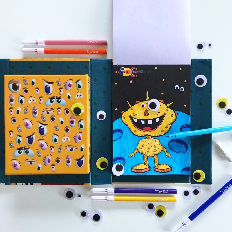 Criança a usar o conjunto Tiger Tribe "Crazy Eyes Creatures", a colorir e a adicionar olhos a um desenho de um extraterrestre.