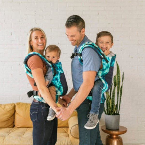 Família com pai, mãe e criança a usarem a Mochila Tula Free-to-Grow Coast - Shoal em diferentes posições.