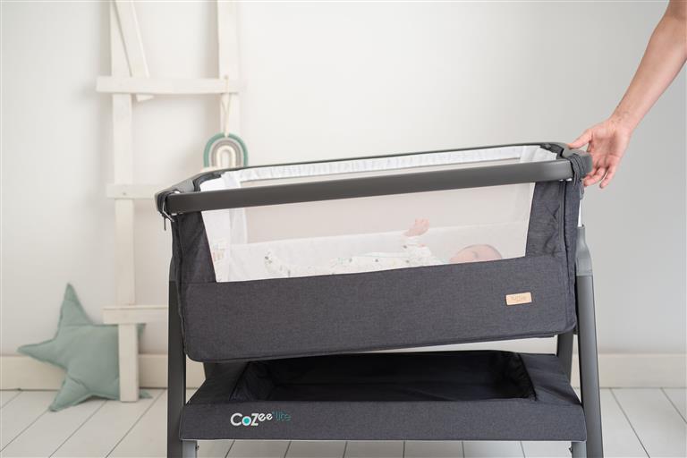 Detalhe do berço CoZee® Lite cinza mostrando o tecido respirável de malha dupla e o interior branco com padrão triangular.