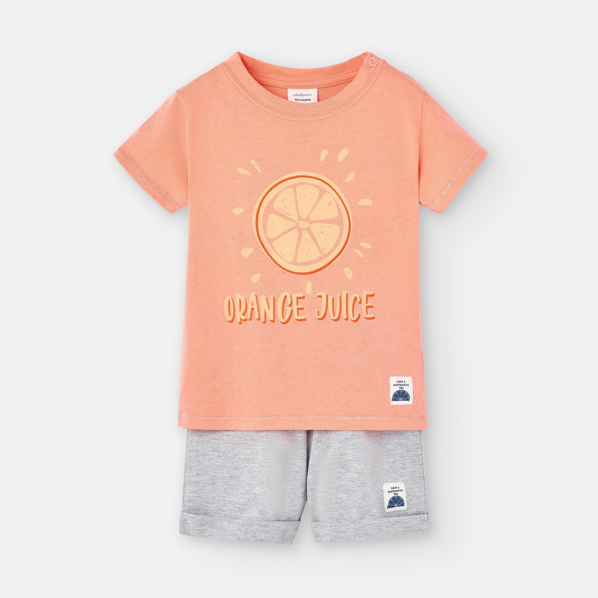 Vista frontal do conjunto de menino Waterlemon: t-shirt salmão com estampa "Orange Juice" e calções cinzentos. Foco no design principal.