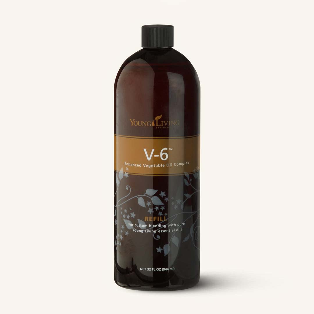 Fundo desfocado com ingredientes naturais, sugerindo a base de óleos vegetais nutritivos do Complexo V6.