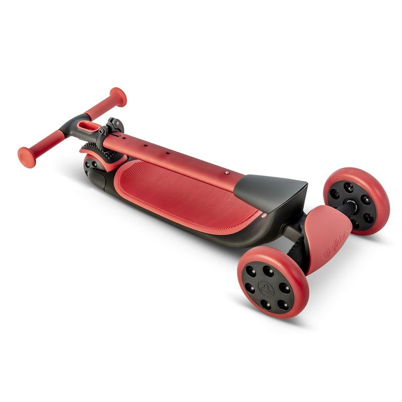 Trotinete Yvolution Nua de 3 rodas dobrada, mostrando o design curvo, a plataforma larga em vermelho e as rodas vermelhas, pronta para transporte ou arrumação.